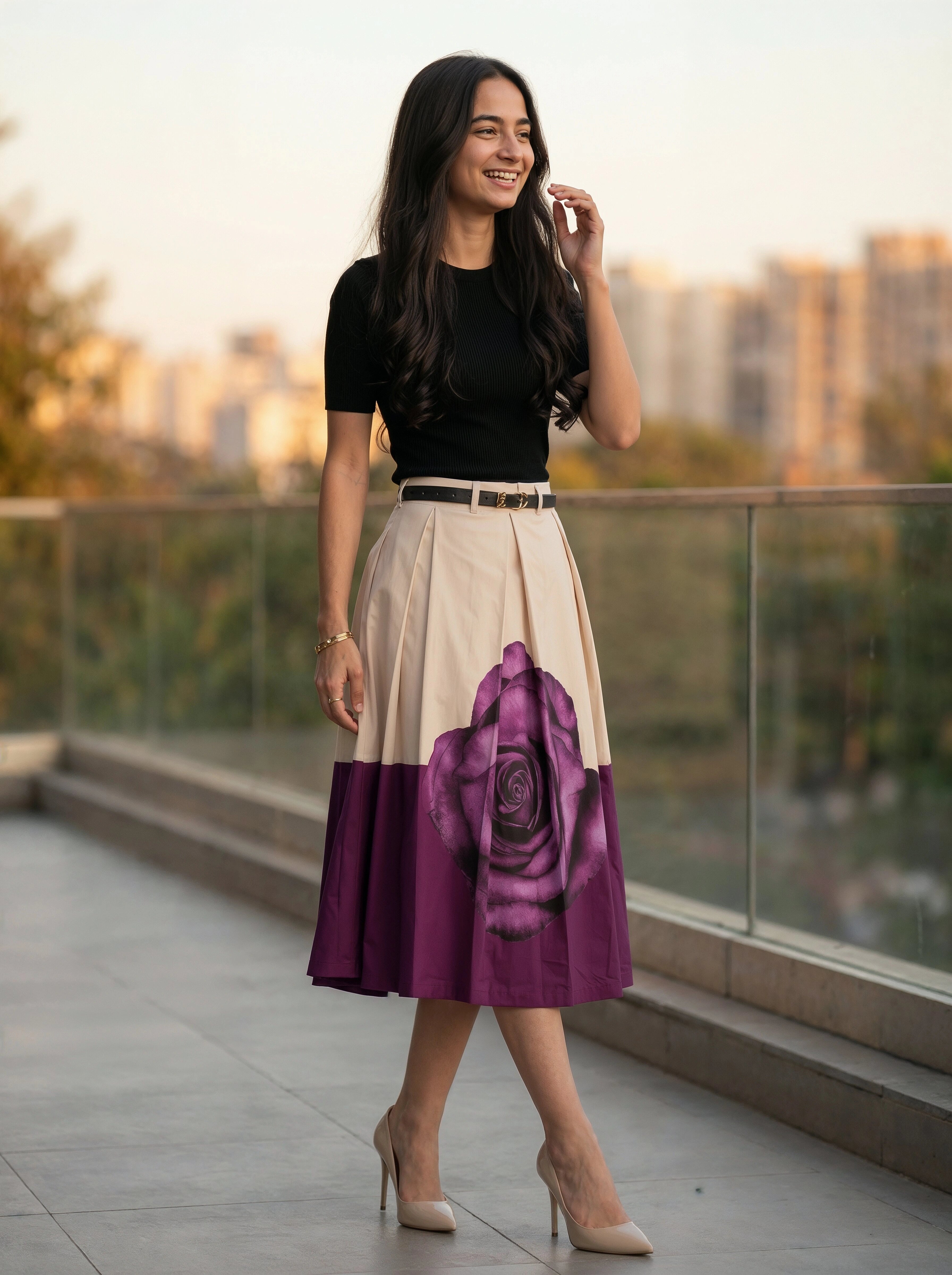 Woman wearing a black top and a purple and beige skirt on a rooftop with cityscape background