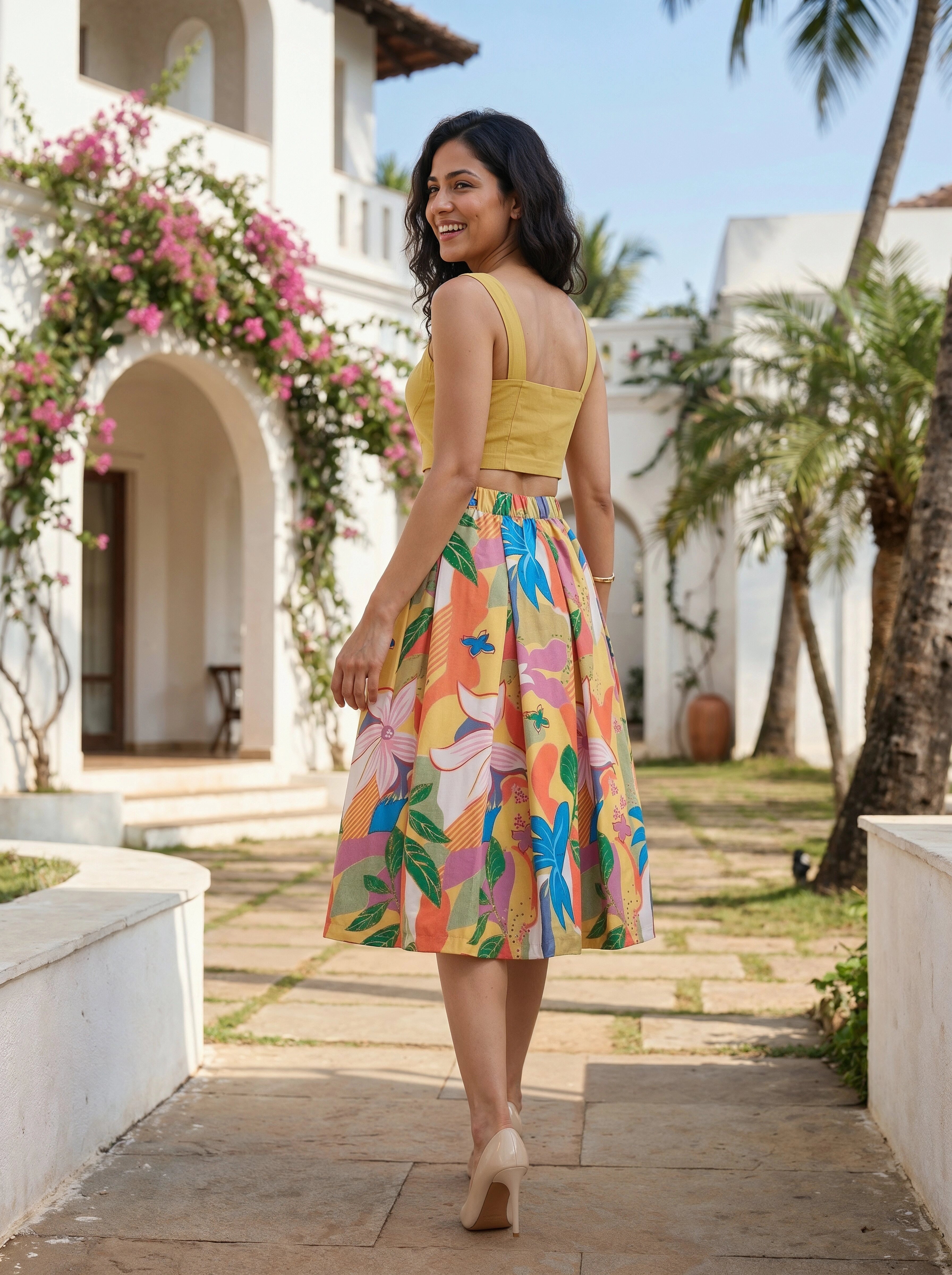 Woman in a colorful dress walking outdoors with a white building and palm trees in the background