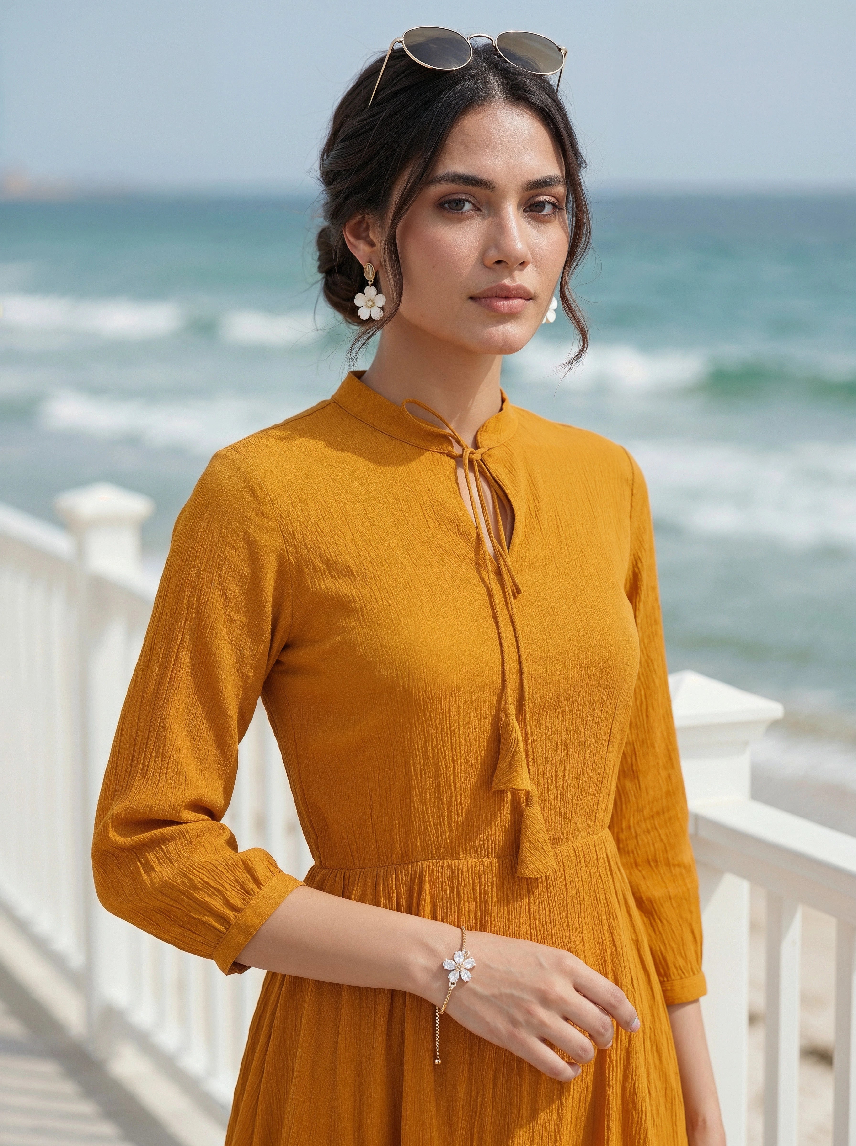 Woman in a mustard yellow dress standing by the ocean