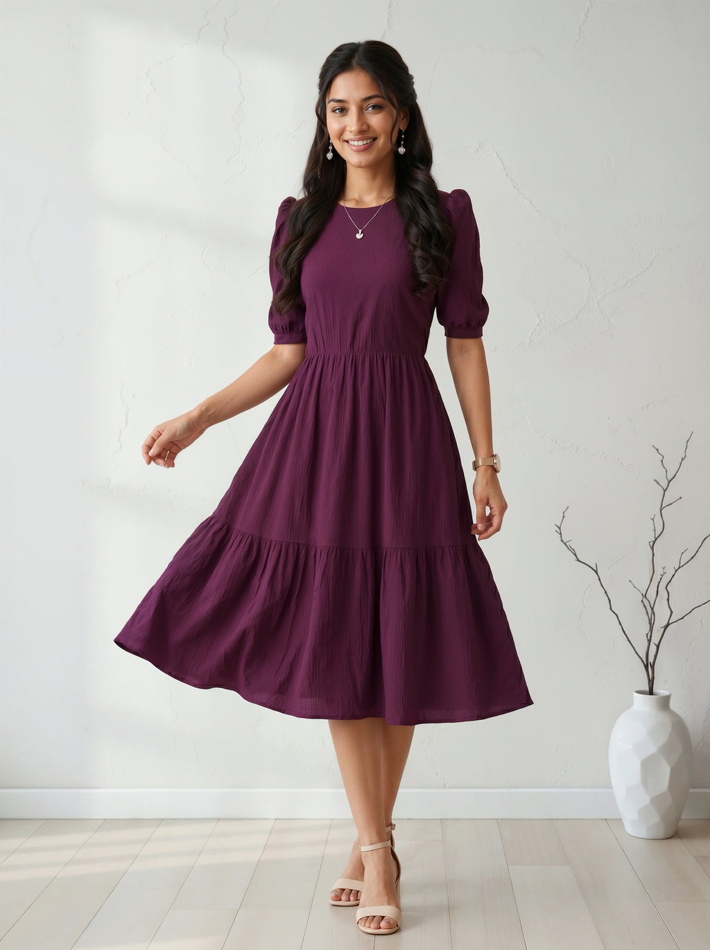 Woman wearing a purple dress standing in a room with a white vase and plant.