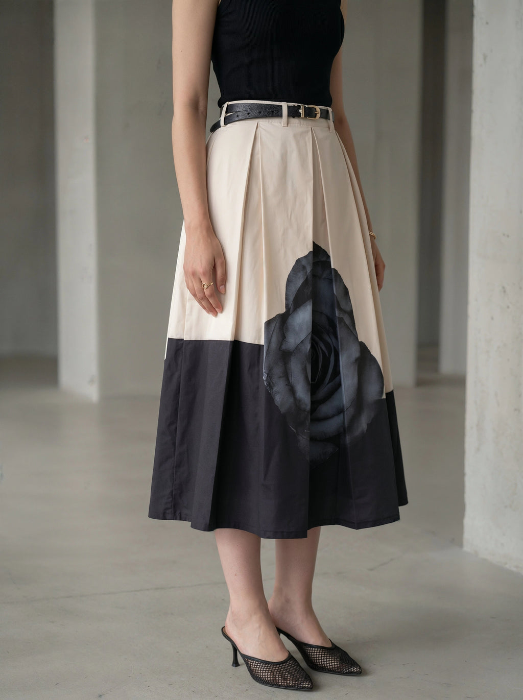 Person wearing a two-tone skirt with a floral design in a minimalistic setting