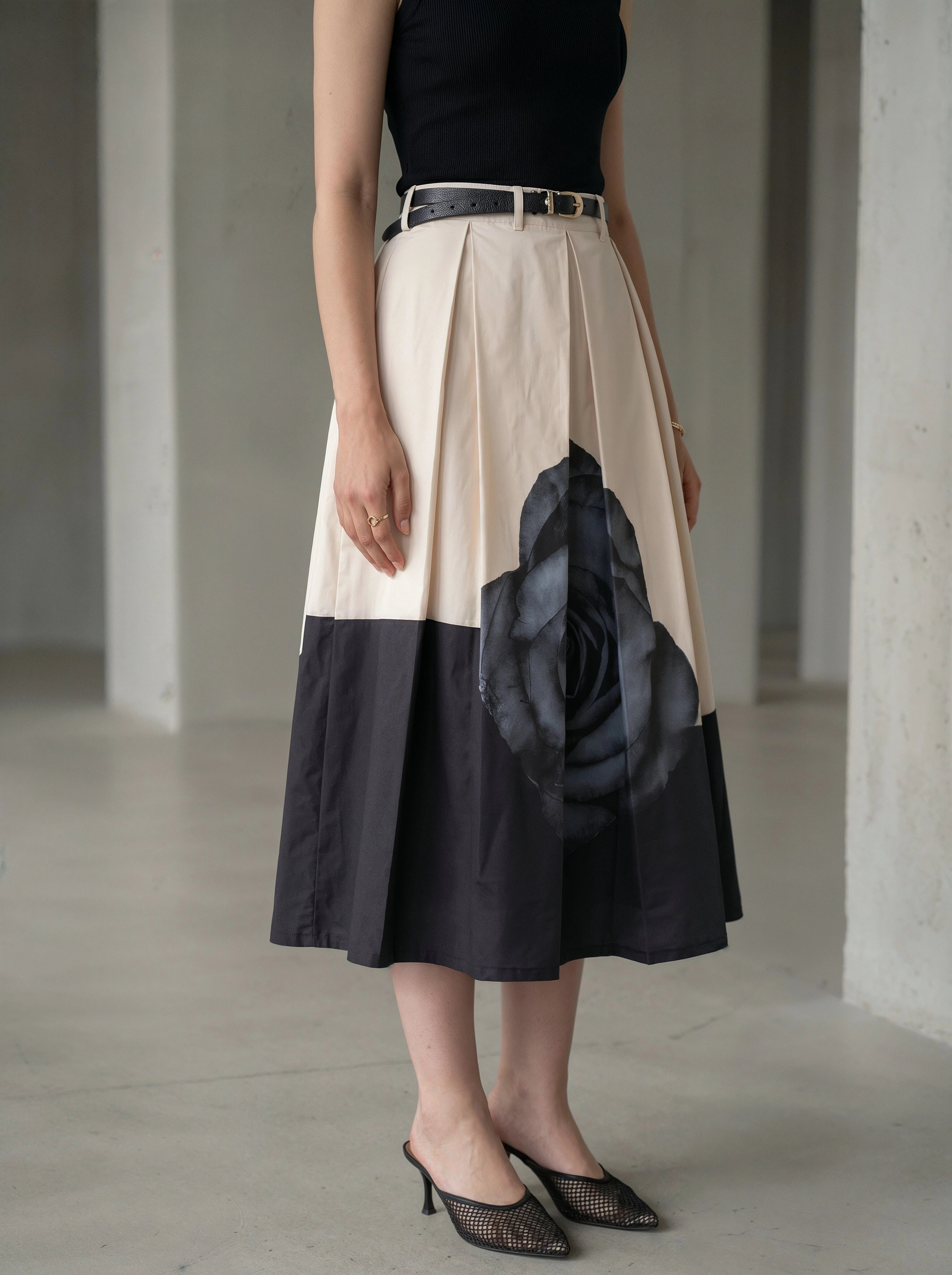 Person wearing a two-tone skirt with a floral design in a minimalistic setting