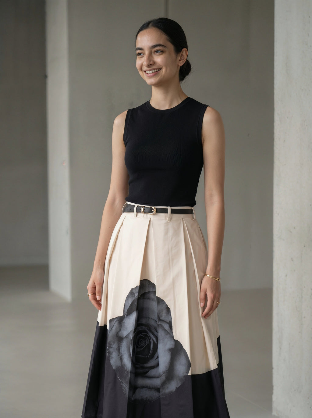 Woman wearing a black top and a floral skirt with a plain background