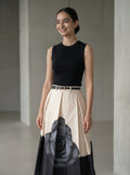 Woman wearing a black top and a floral skirt with a plain background