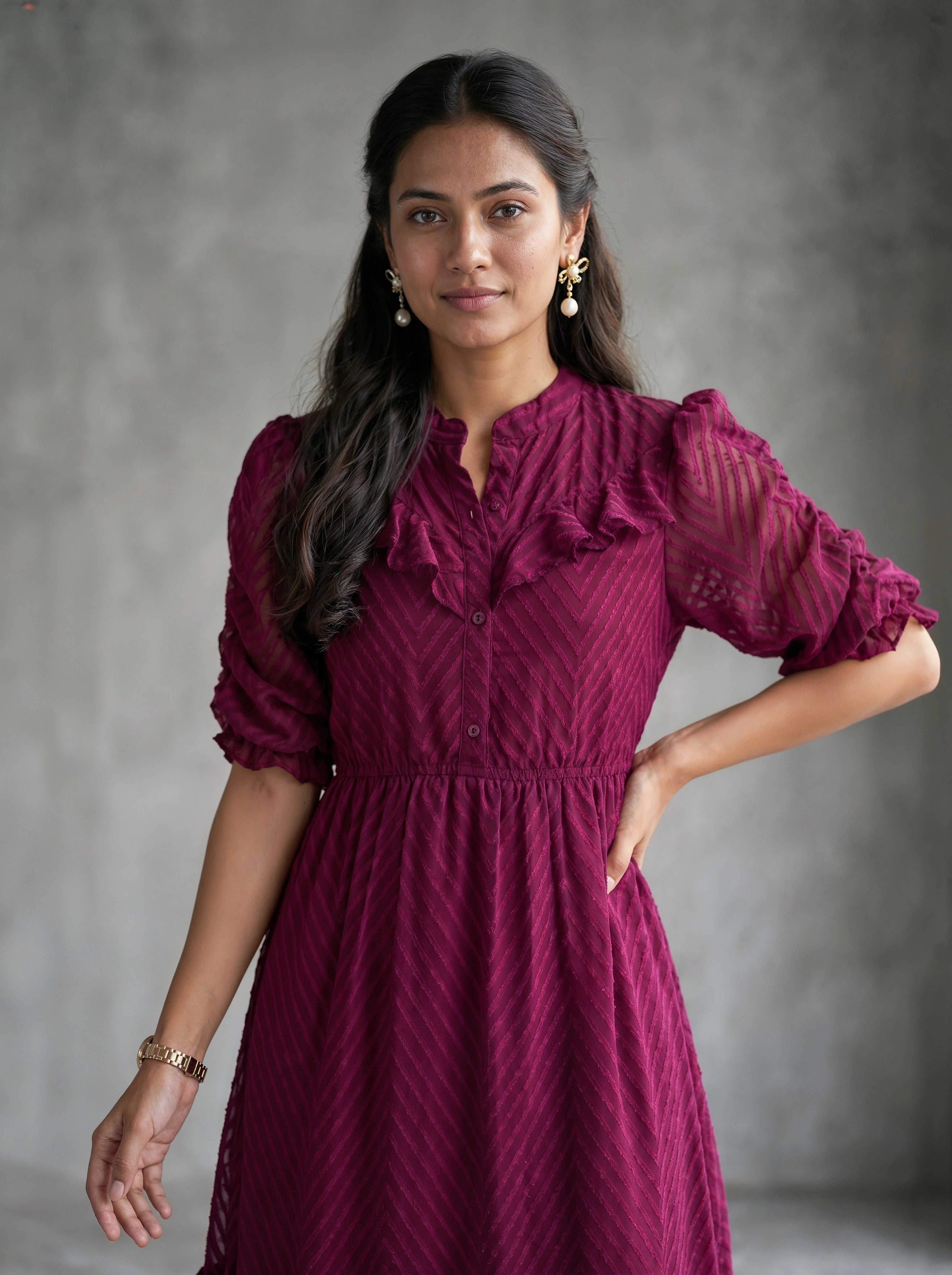 Woman wearing a burgundy dress with long sleeves against a beige background
