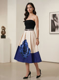 Woman wearing a black top and a colorful skirt with a blue rose design in an indoor setting.