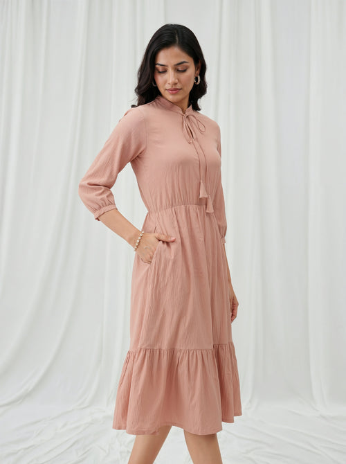 Woman wearing a cream dress against a white curtain background