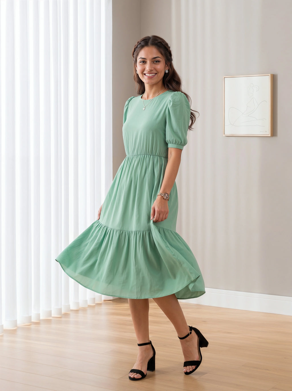 Woman wearing a green dress standing in a room with light-colored walls and wooden floor.