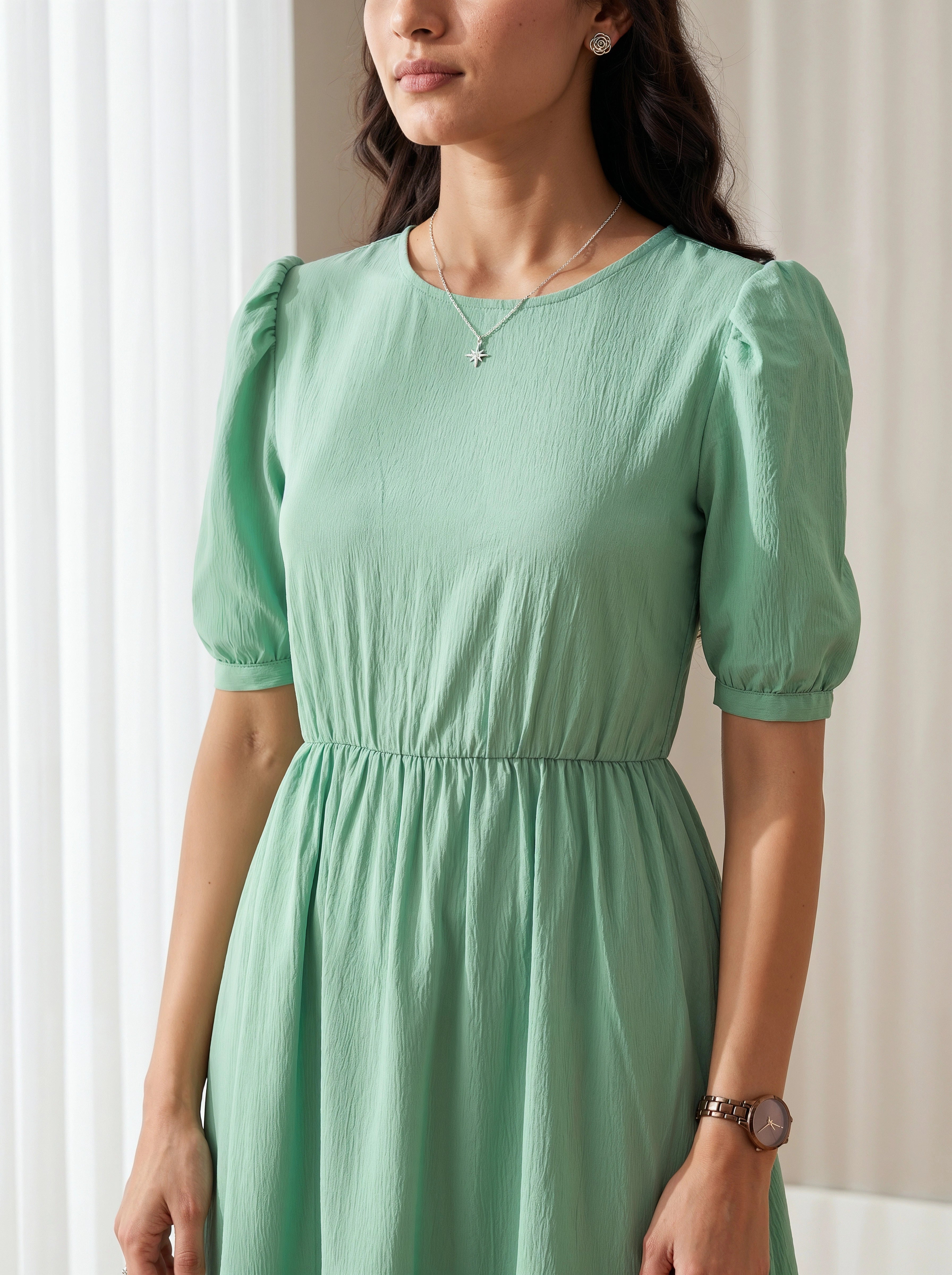 Woman wearing a green dress with puff sleeves against a neutral background