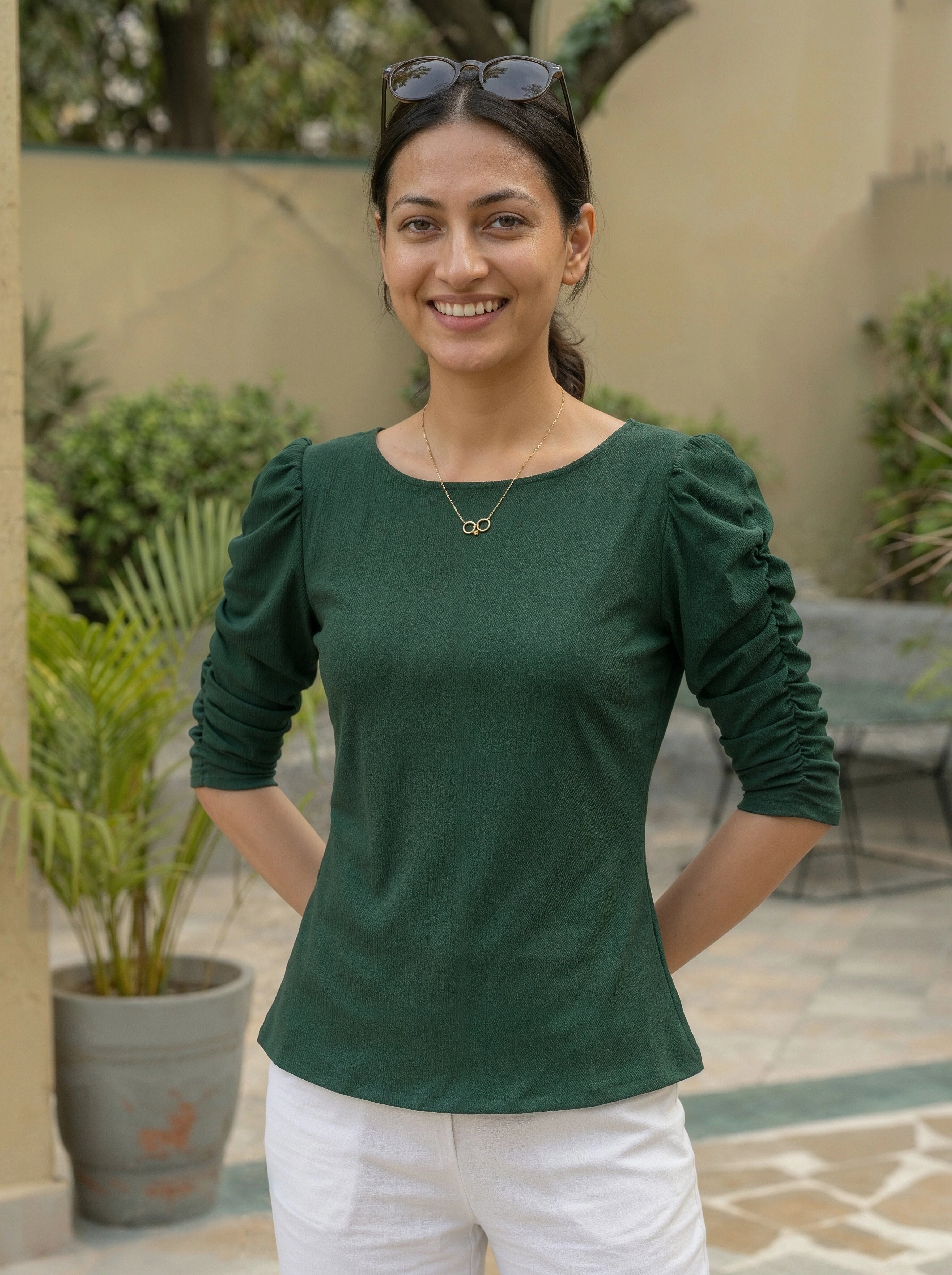 Woman wearing a green top with puffed sleeves standing outdoors.