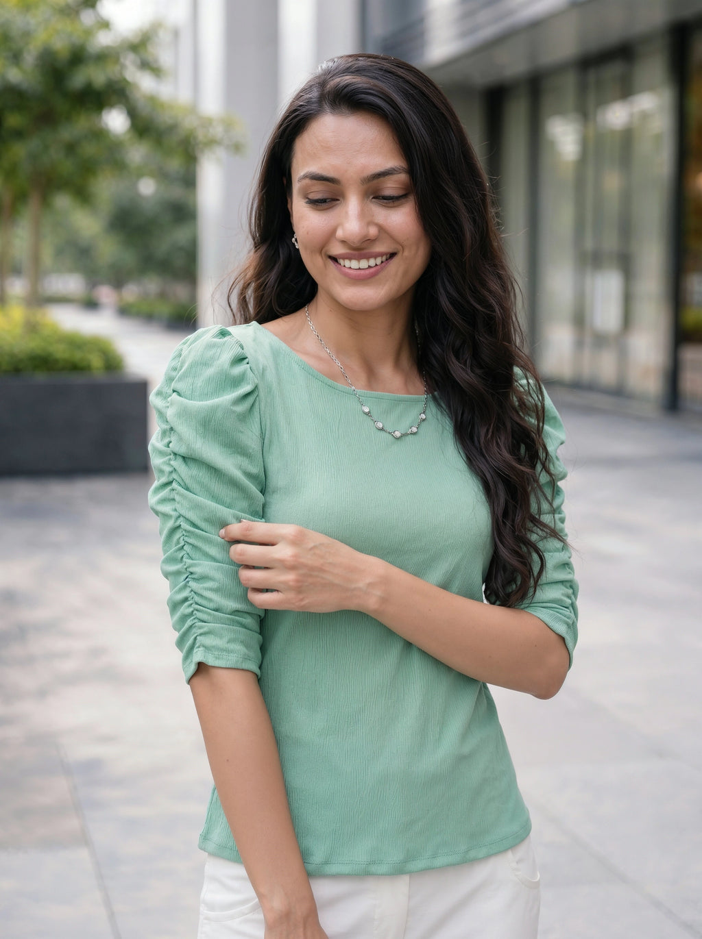 Woman wearing a green top with ruffled sleeves outdoors.
