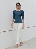 Modern minimalist style outfit with a teal puff-sleeve shirt and crisp white pants.