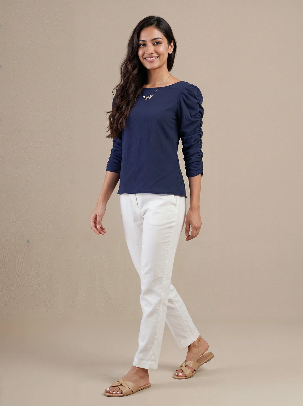 Woman wearing a navy blue top and white pants on a beige background