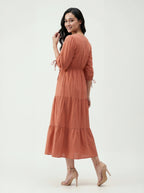 Woman wearing a long rust-colored dress on a white background