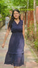 A woman wearing a navy blue chevron-patterned sleeveless dress with a v-neckline walking on a stone path