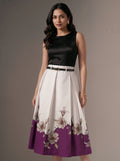 Woman wearing a black top and floral skirt with purple base on a gray background