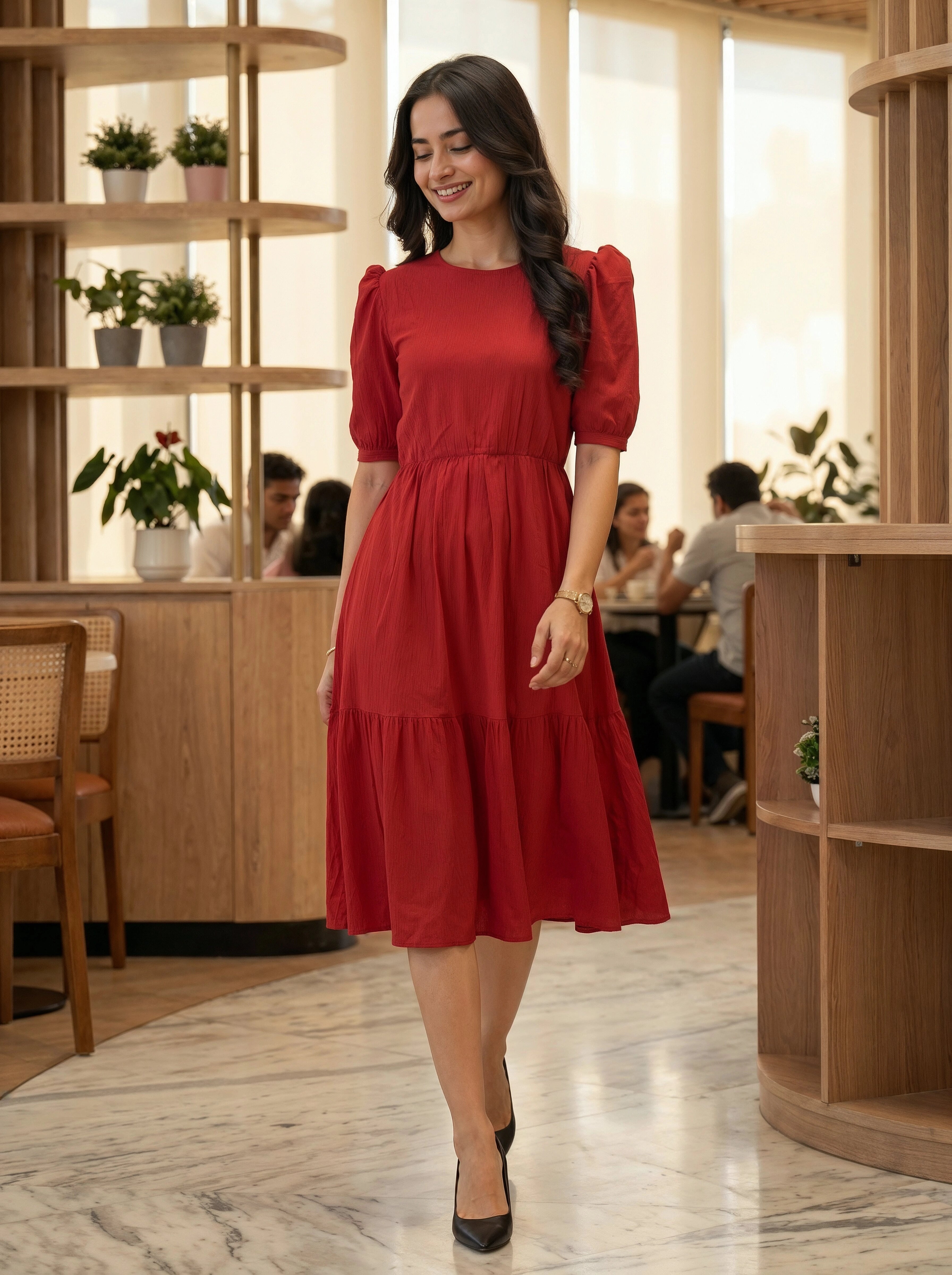 Woman in a red dress standing in a modern cafe.