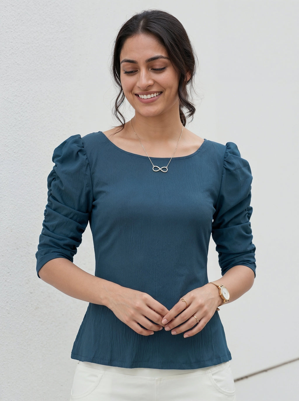 Woman wearing a teal blouse with puffed sleeves against a light background