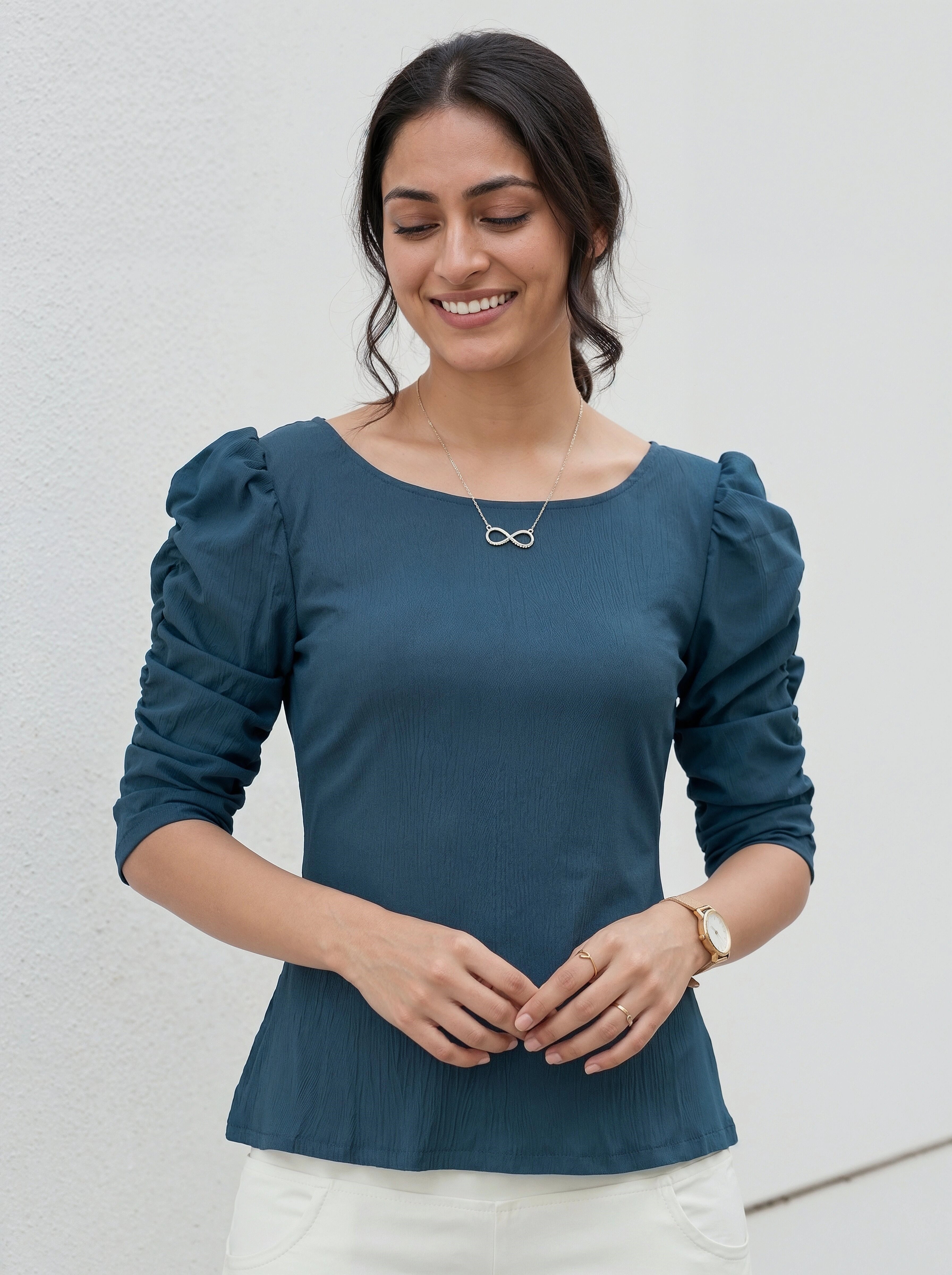 Woman wearing a teal blouse with puffed sleeves against a light background