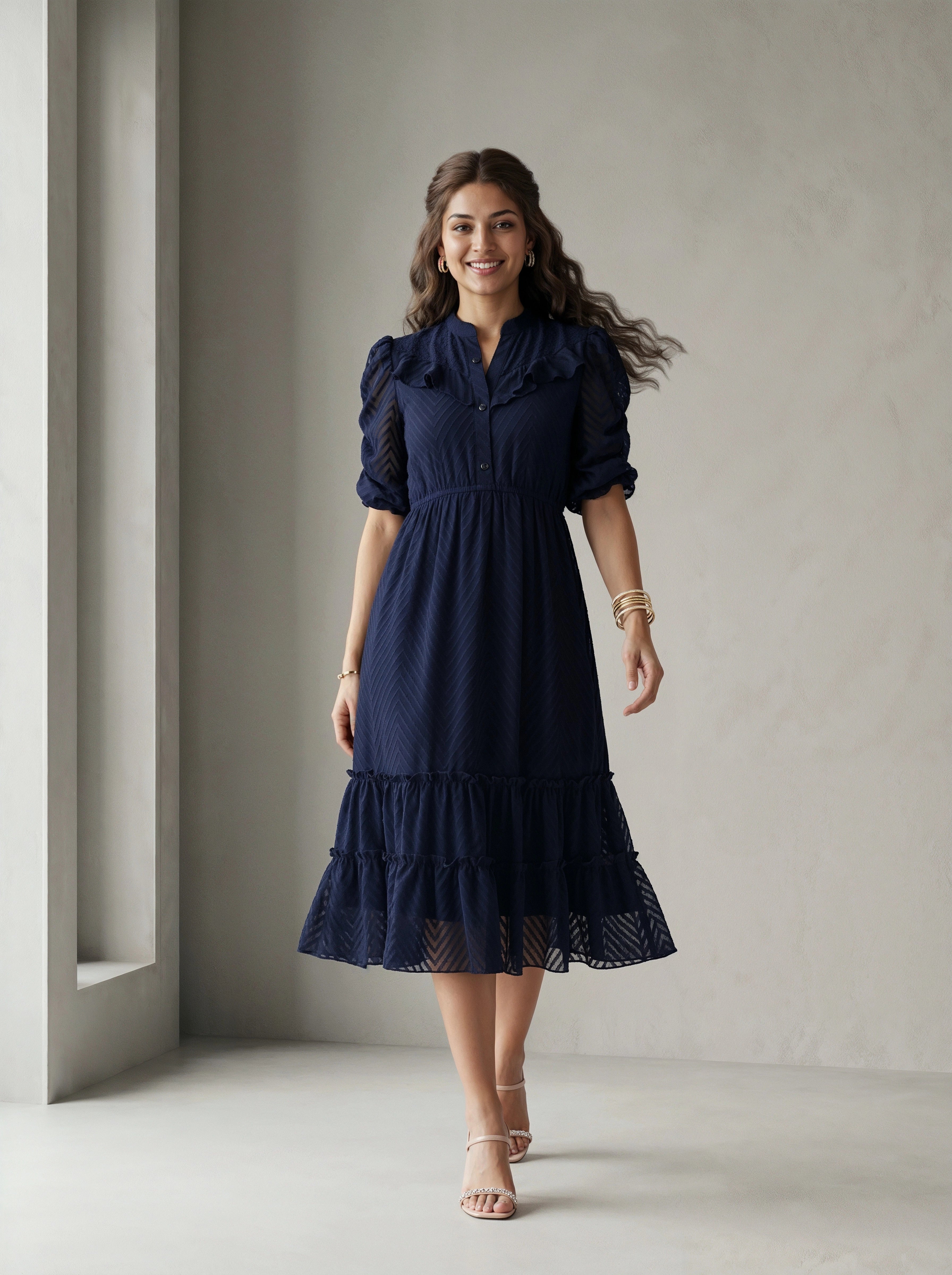 Woman wearing a blue dress standing in front of a white wall with a window.